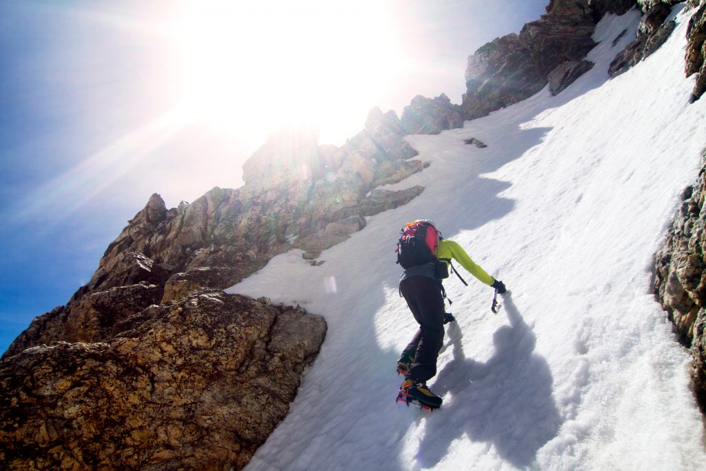 low angle view of man climbing snow covered mountain